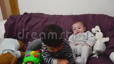 可爱的两岁男孩在玩海龟教育玩具，而他的小弟弟正在看着和微笑